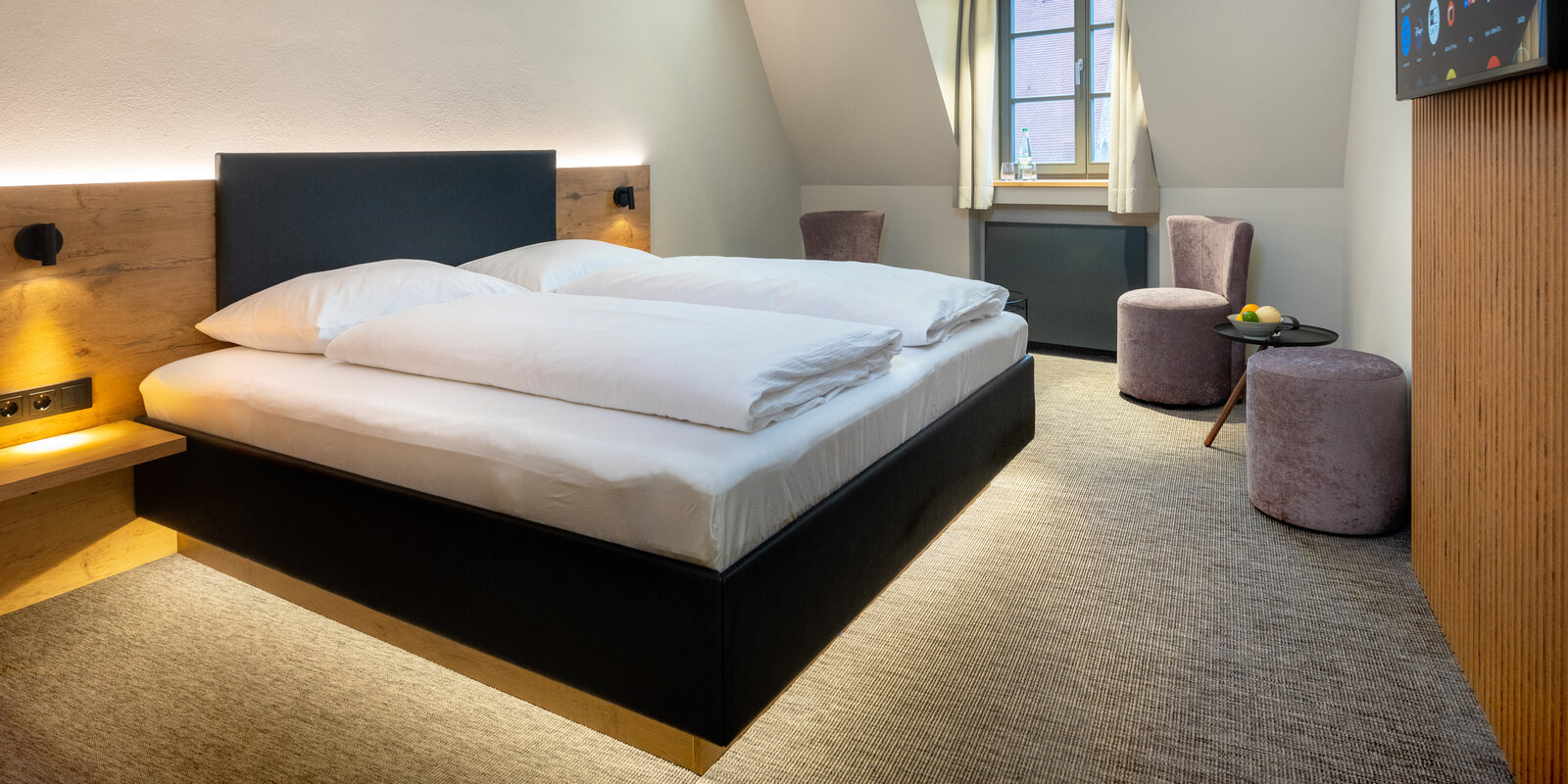 Zieflekoch Hotel Nashi Erfurt Modern hotel room with a large bed, white bedding, wooden accents, two purple chairs, a small table with fruit, and a window with curtains.