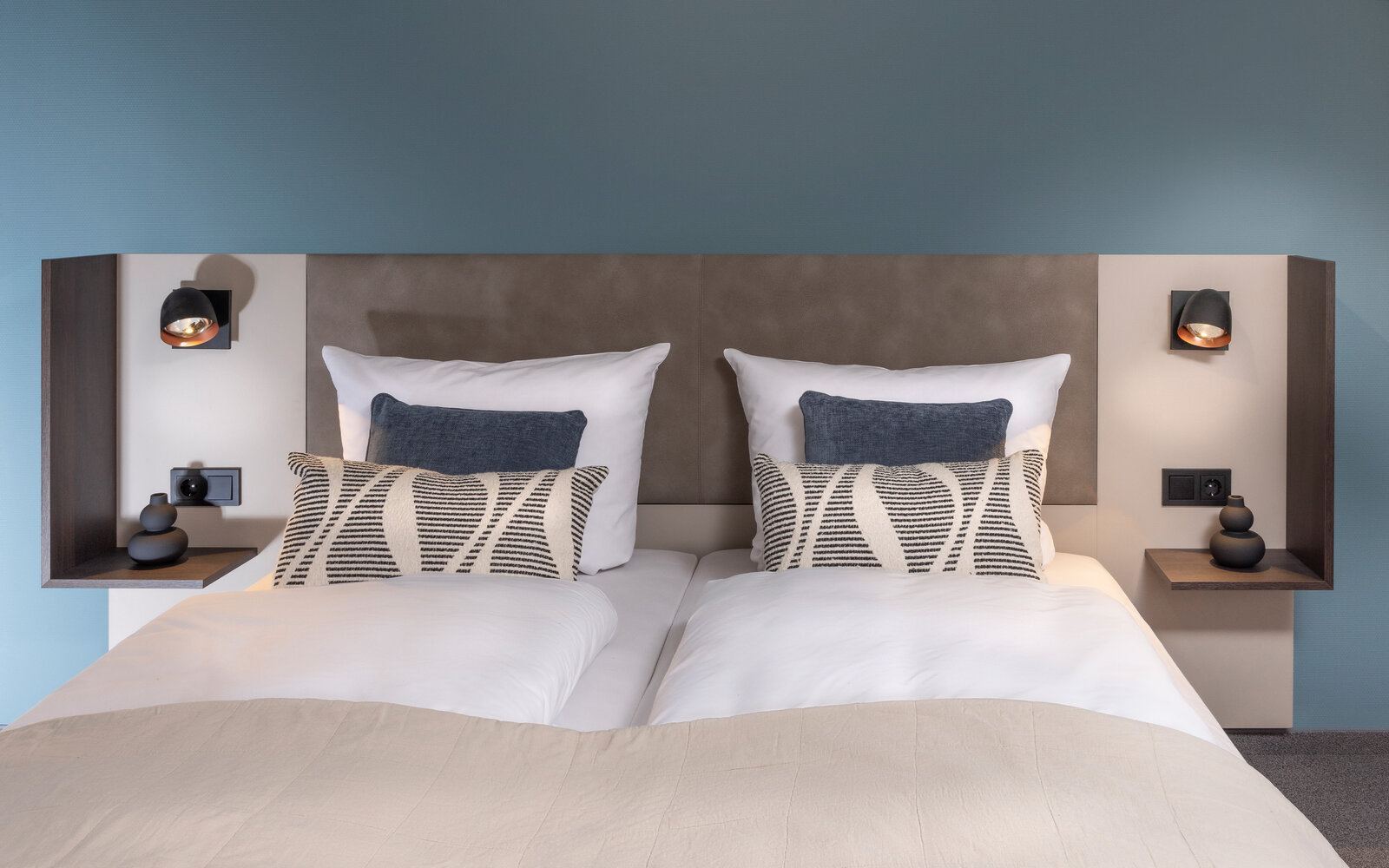 Hotelbettmodul mit Nachtkästchen vor türkieser Wand