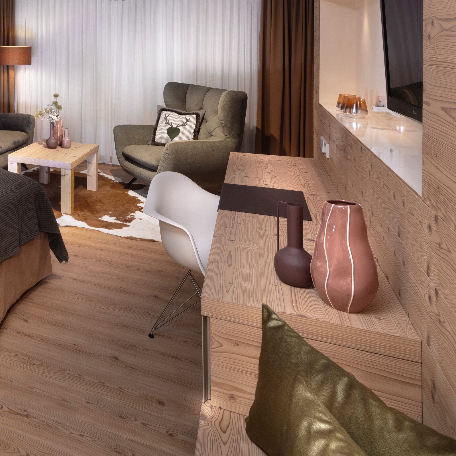 zieflekoch musterzimmer zulux, modernes Zimmer mit Holzdekor, wandmontiertem Fernseher, Schreibtisch mit Stuhl und anschliessender Sitzbank, gemütlichem Sessel und einem Bett mit dunkler Strukturdecke.