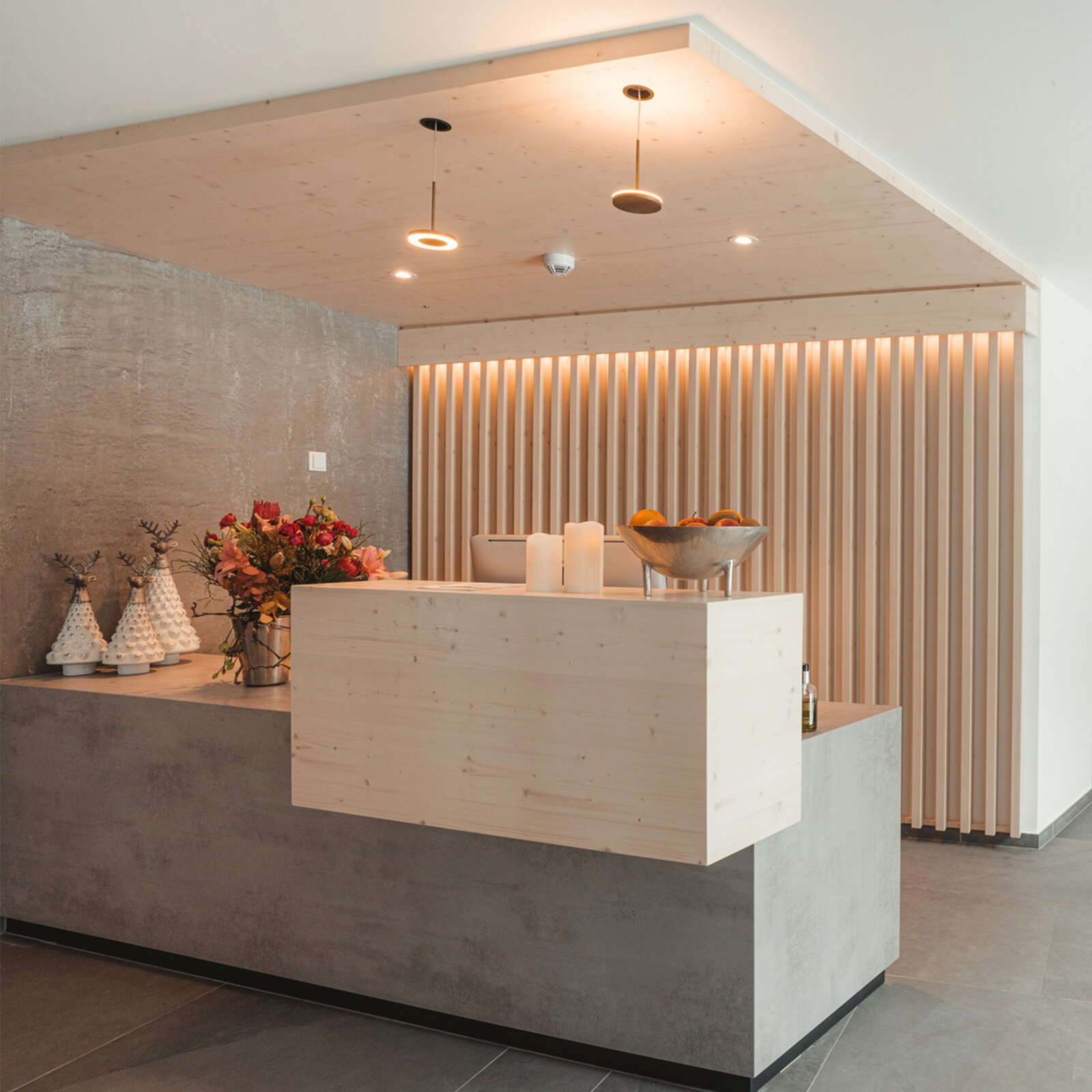 zieflekoch Alpen Resort Empfang Rezeption Lobby Holzwand Holz Sessel Sitzecke Beton