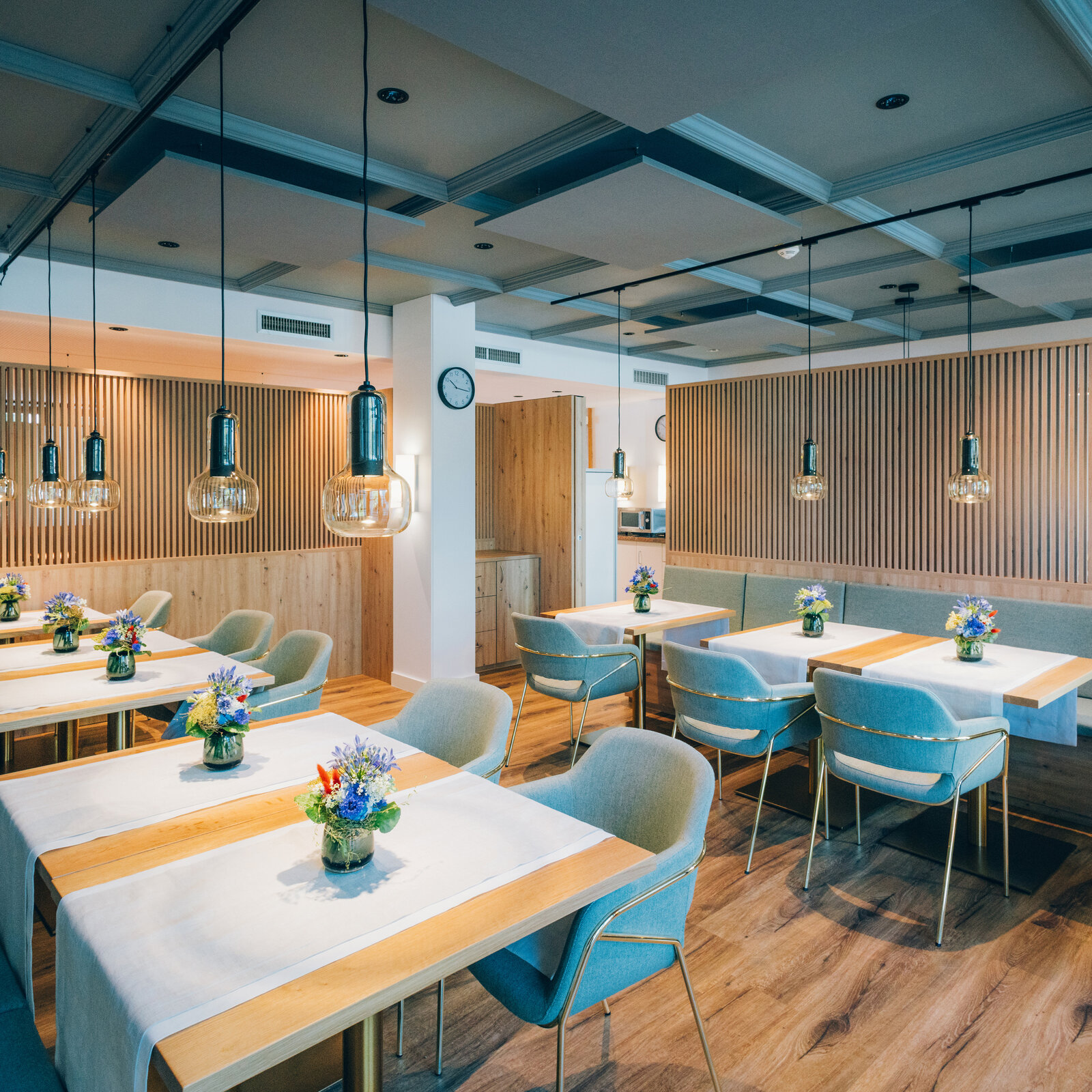 Kantine mit blauen Polsterstühlen, Polsterbänken und Lamellenwände aus Eiche zur Abtrennung