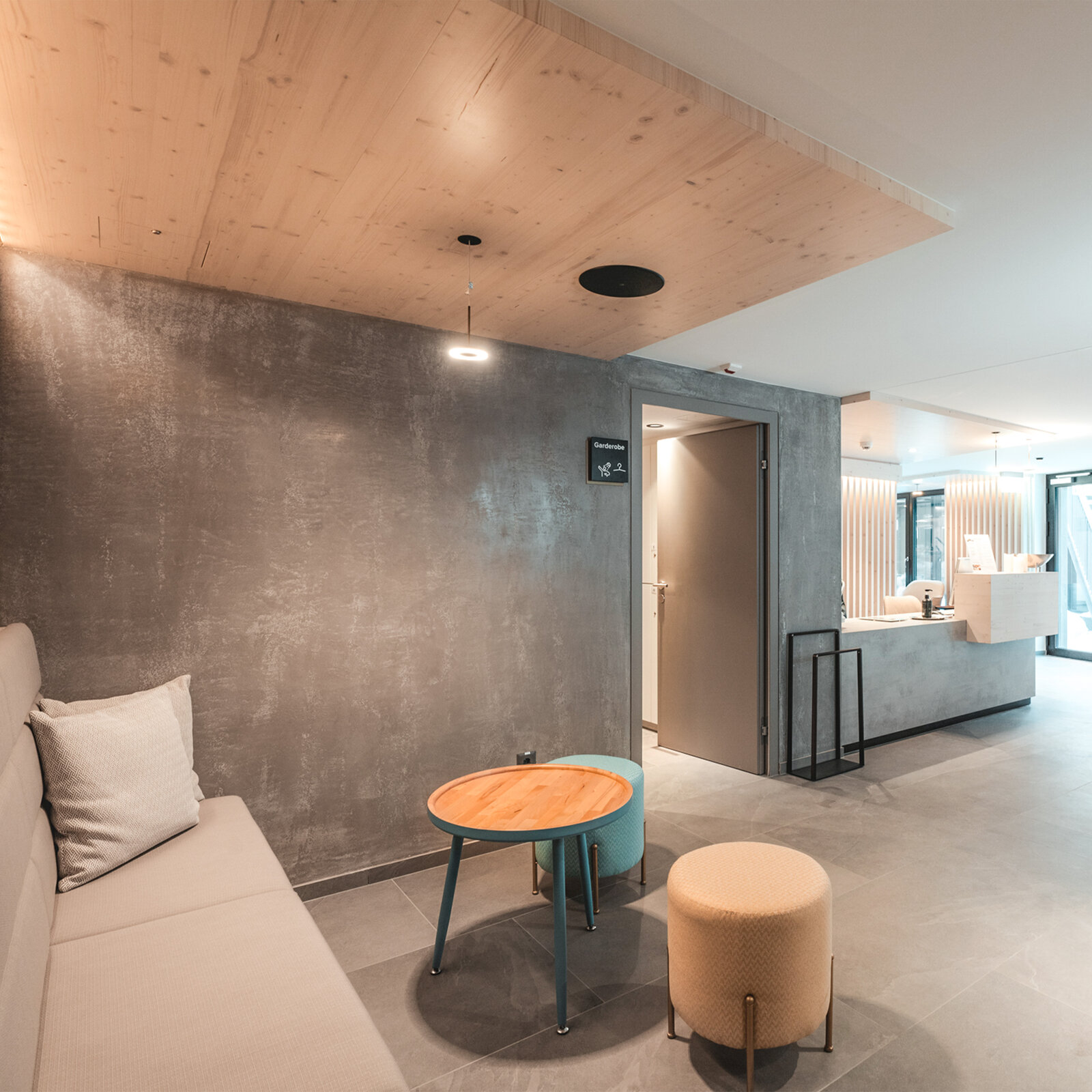 zieflekoch Alpen Resort Empfang Rezeption Lobby Holzwand Holz Sitzbank Sitzecke Beton