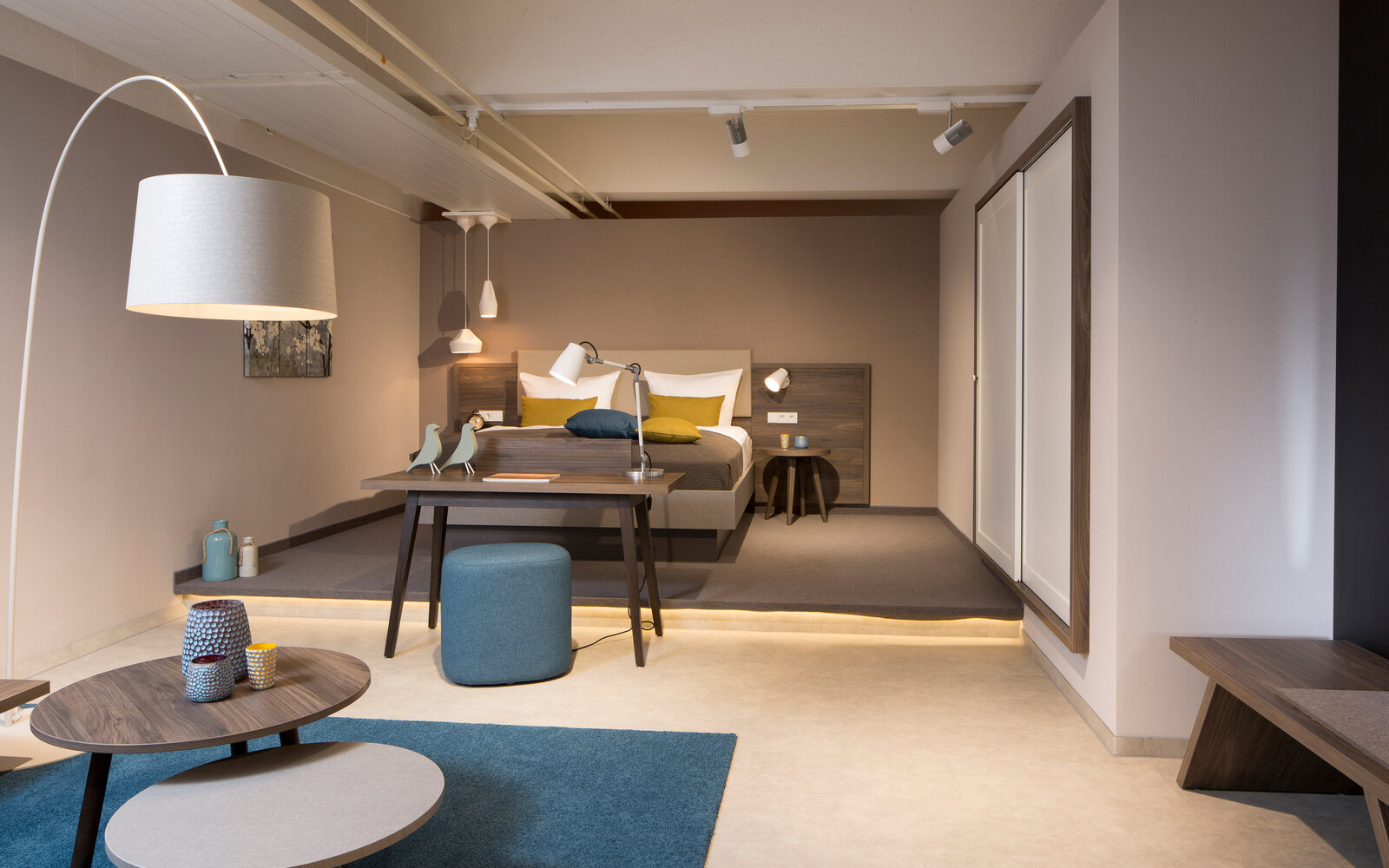zieflekoch musterzimmer zand zimmer holz bett doppelbett schrank einbauschrank schiebetueren stehlampe tisch bank beistelltisch lampe leuchten hocker