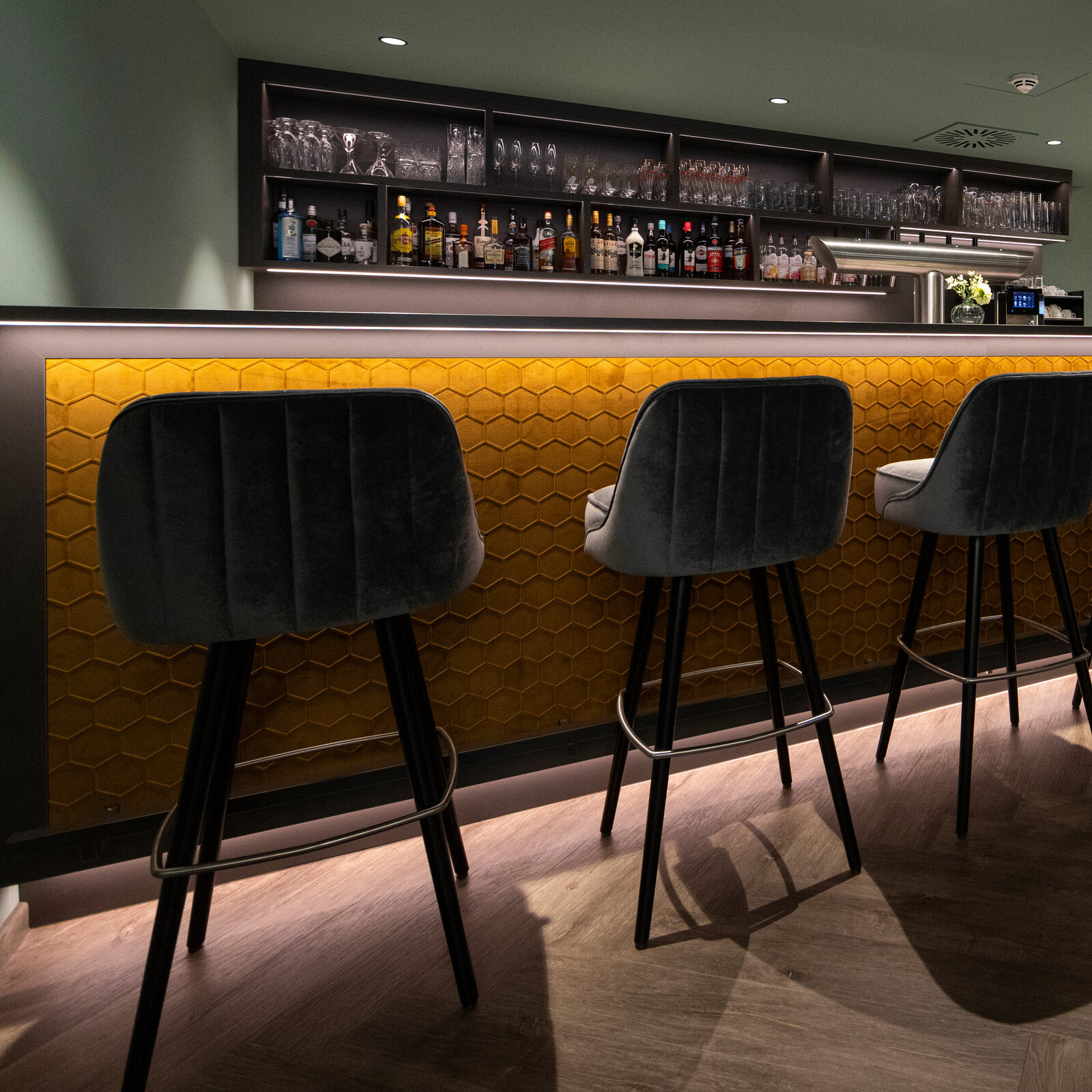 zieflekoch hotel fulda mitte graue dekorflaechen holzflaechen kastanie goldfarben schallschutzoberflaechen wabenform gruentoene wandbilder sessel hocker tische polsterbaenke restaurant bar lounge marmoroptik