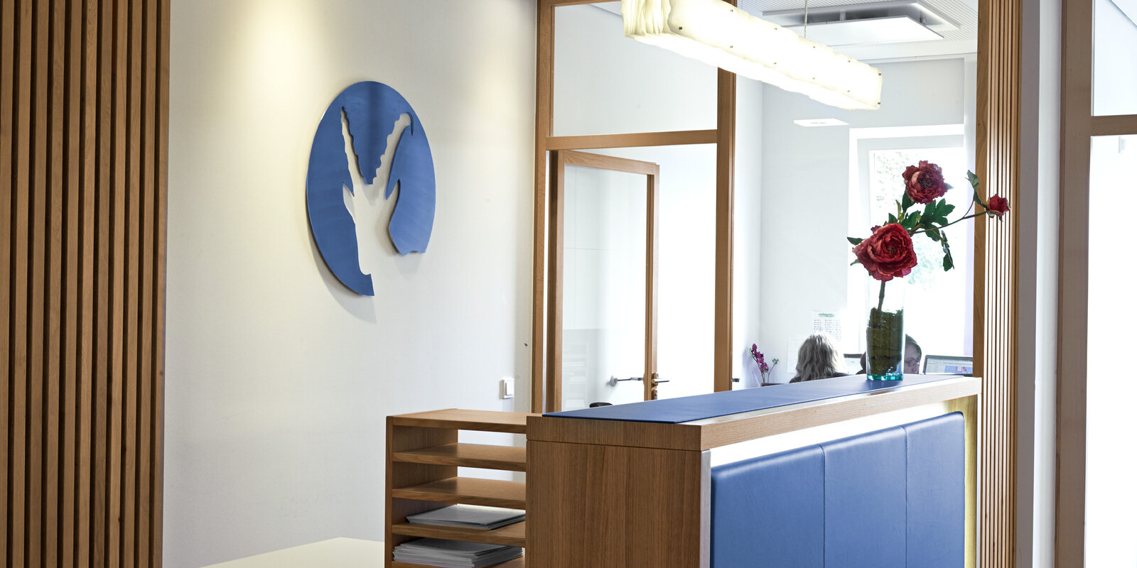 zieflekoch Fachklinik Klinik im Alpenpark Zimmer Empfang Holzwand Logo Regal Holz