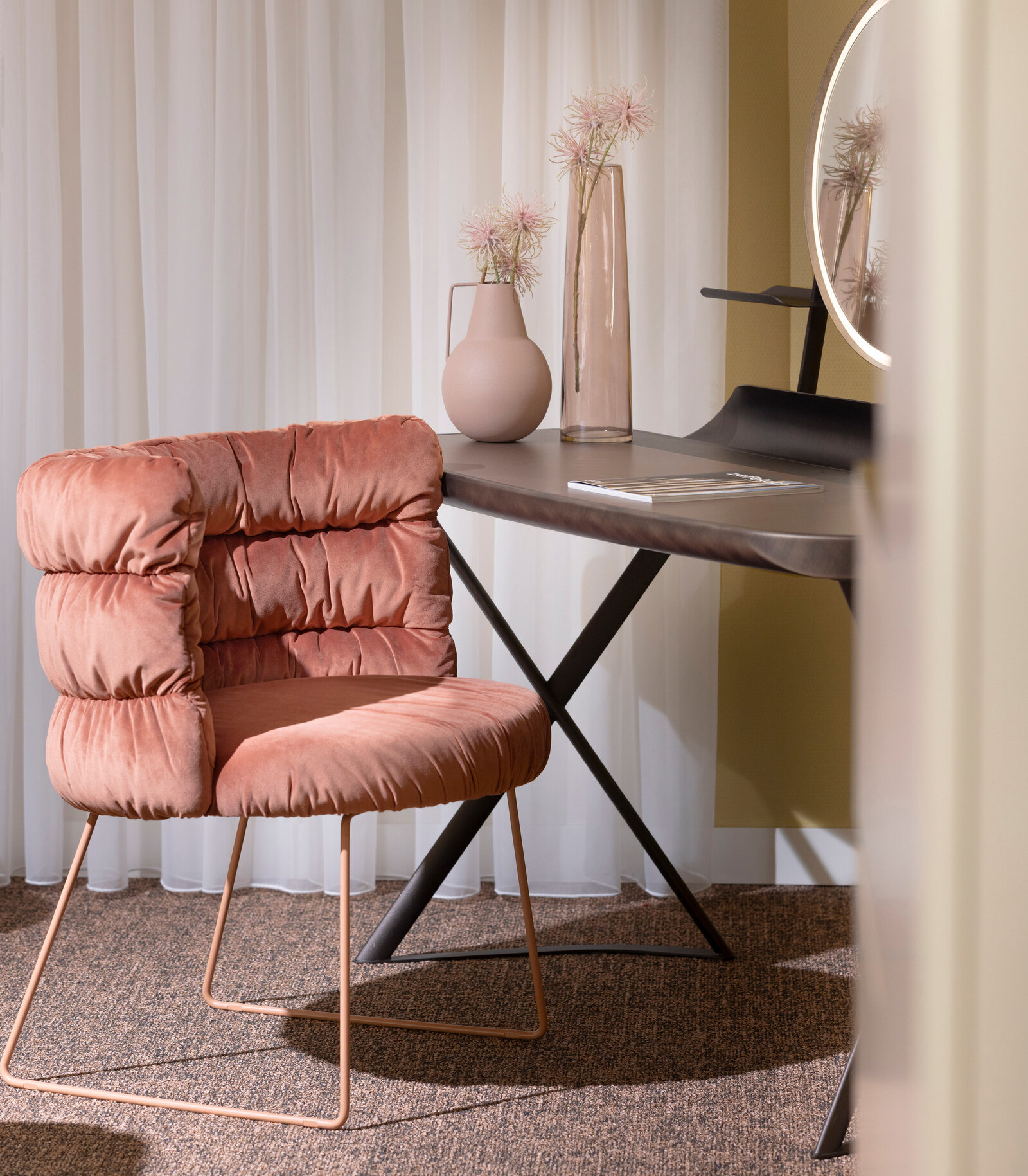 A cozy room with a plush pink chair, a sleek black desk, and decorative vases. Soft lighting and sheer curtains create a warm ambiance.