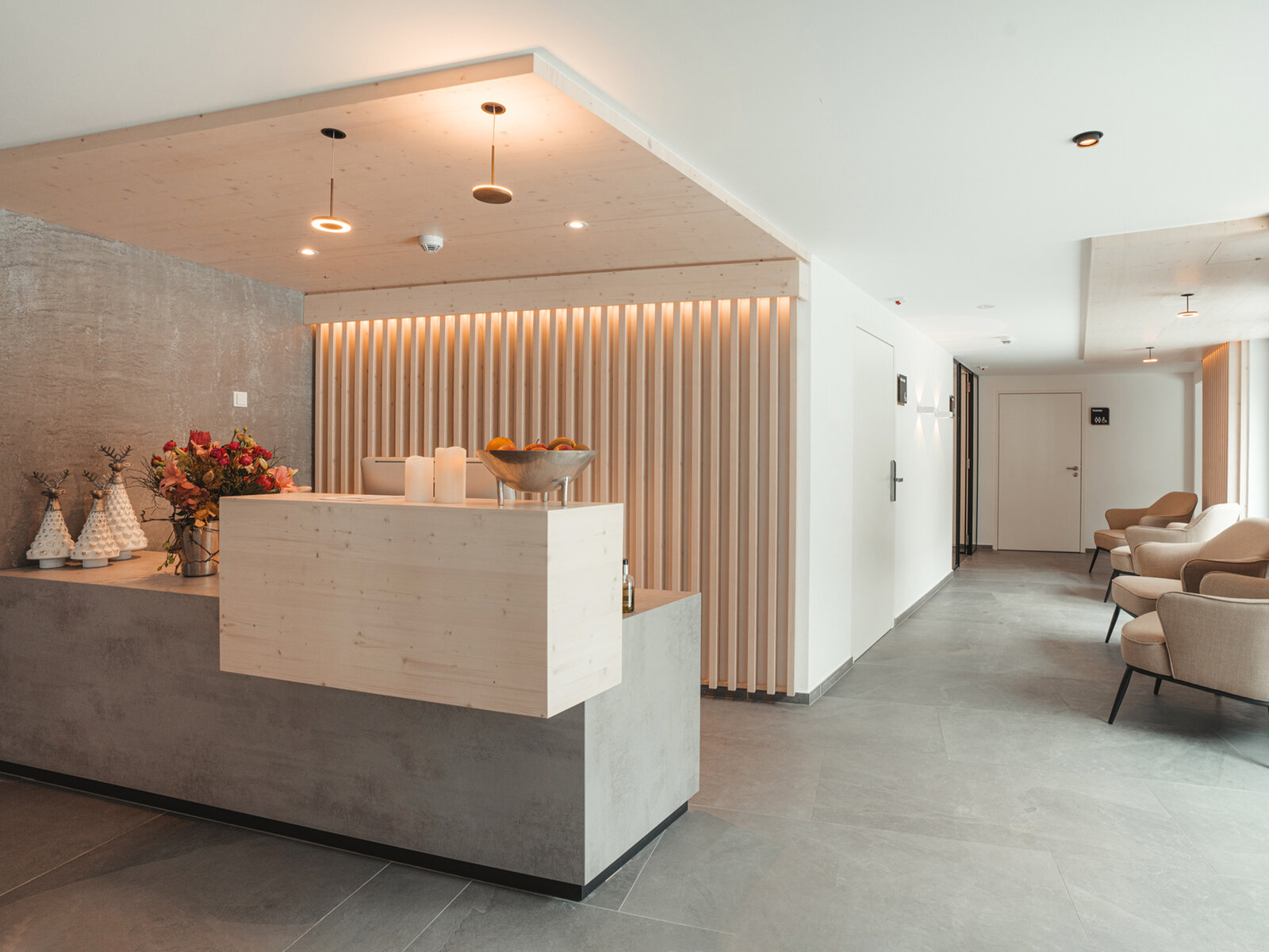 zieflekoch Alpen Resort Empfang Rezeption Lobby Holzwand Holz Sessel Sitzecke Beton