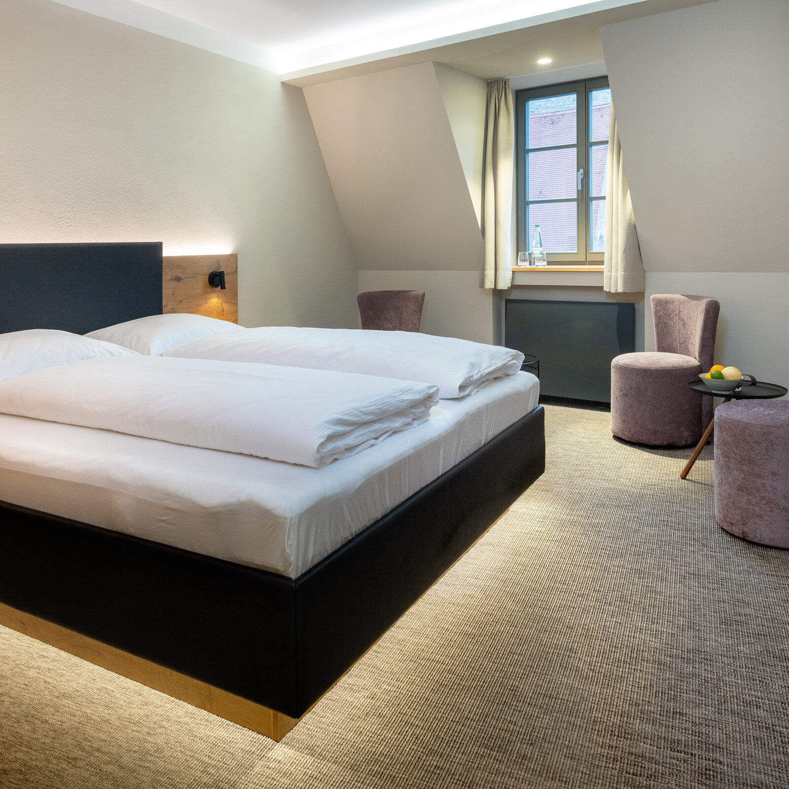 Zieflekoch Hotel Nashi Erfurt Modern hotel room with a large bed, white bedding, wooden accents, two purple chairs, a small table with fruit, and a window with curtains.