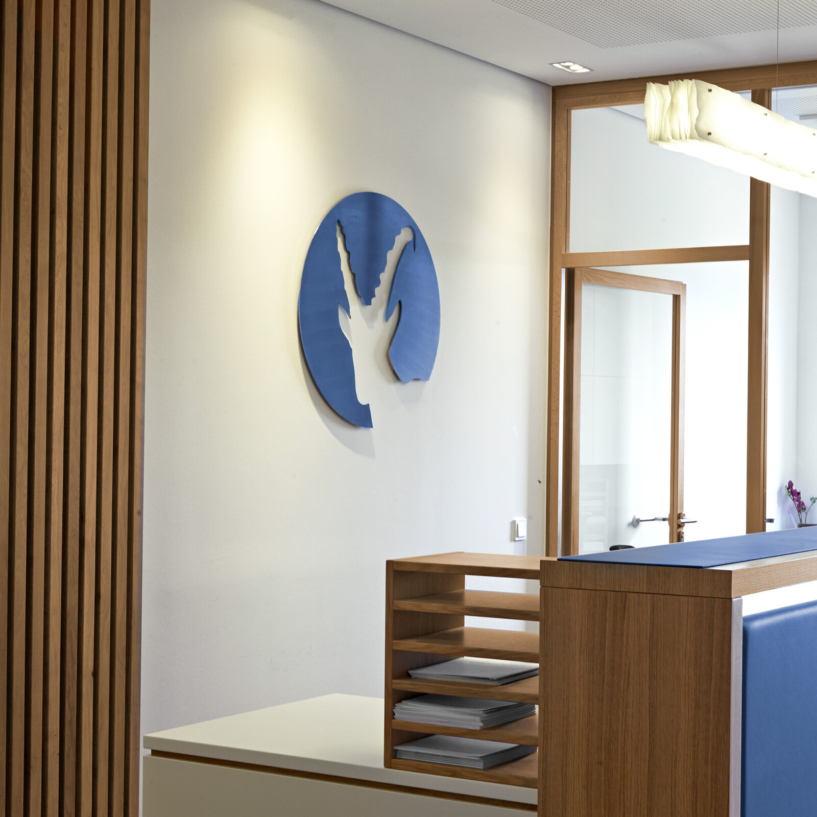 zieflekoch Fachklinik Klinik im Alpenpark Zimmer Empfang Holzwand Logo Regal Holz