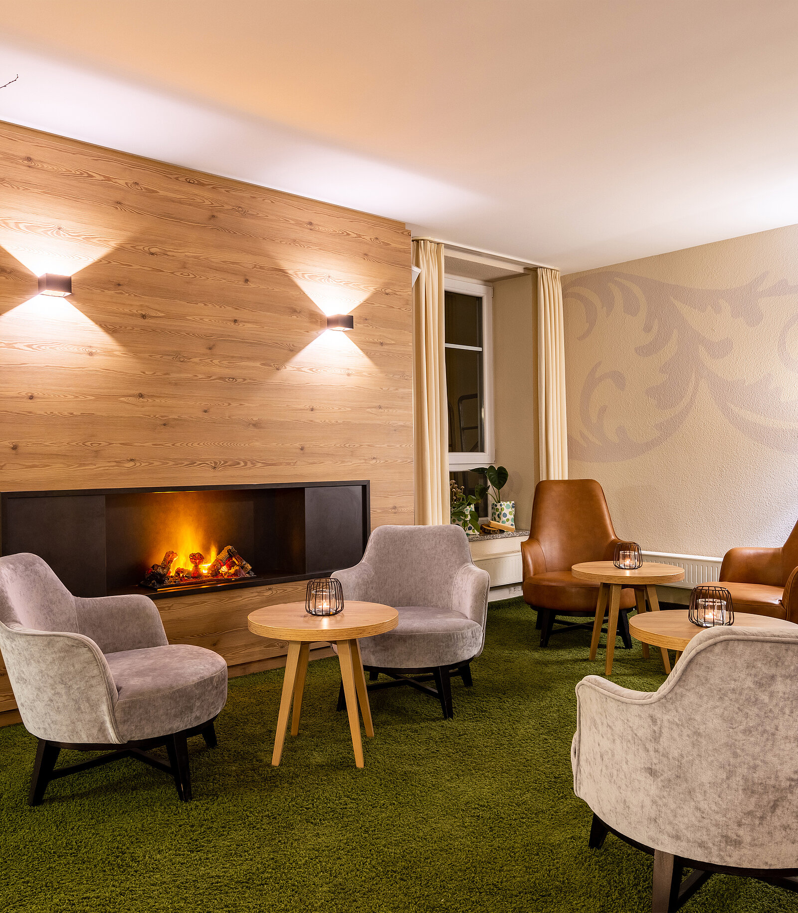 lobby mit bequemen sesseln, teppich und feuertstelle im parkhotel maximilian ottobeuren