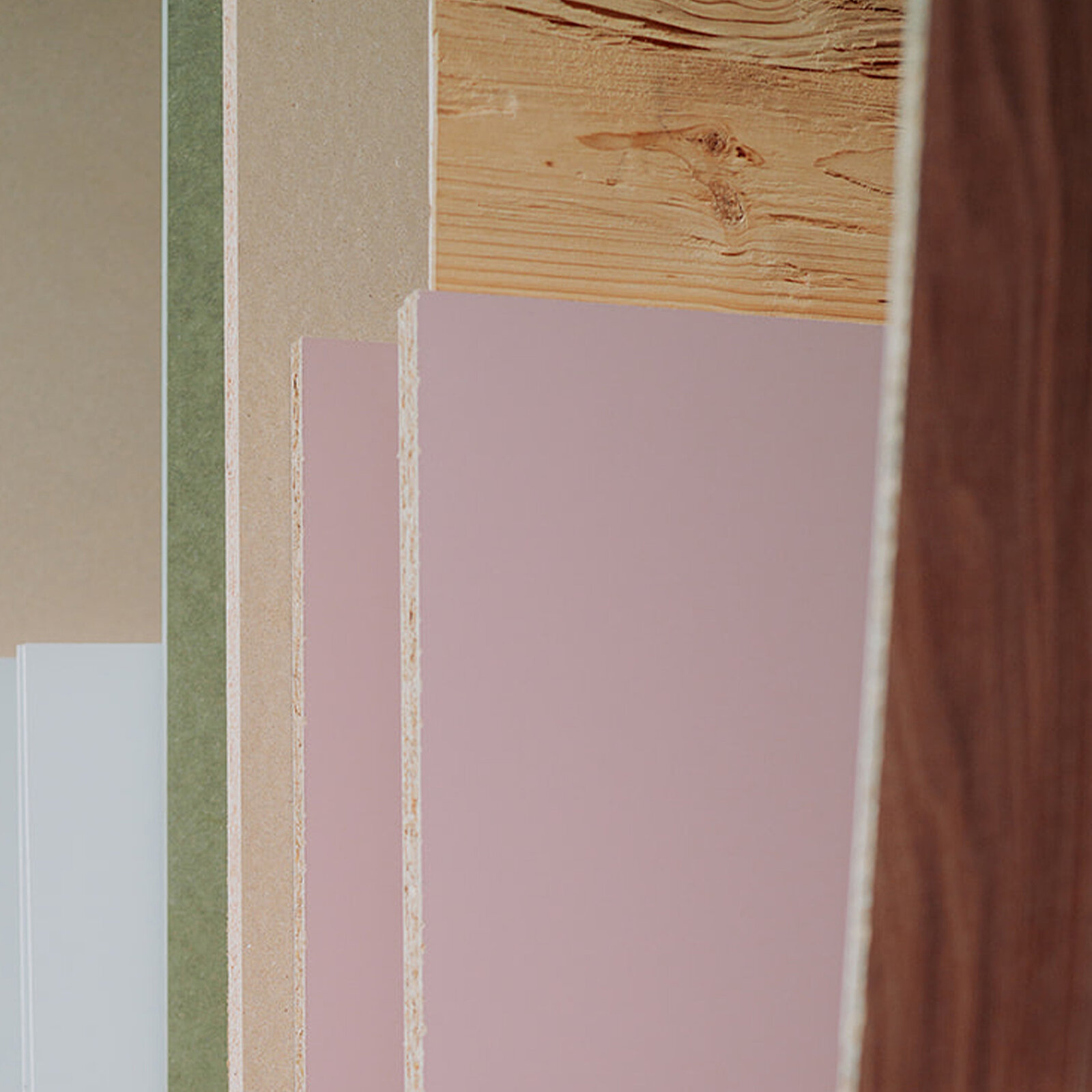 A variety of colorful laminate boards, including pink, green, and wood textures, are arranged vertically in a row.
