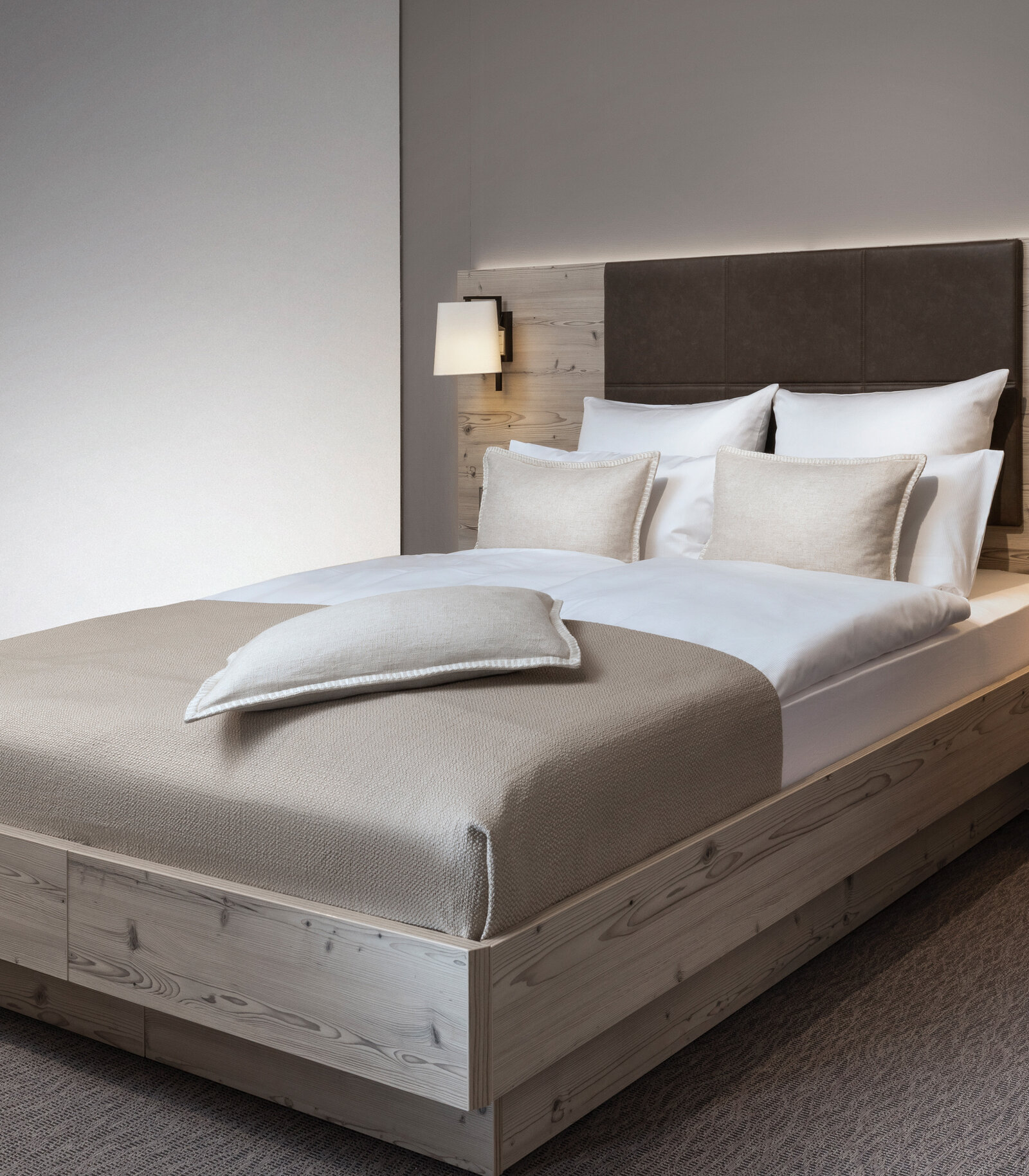 Hotelbett aus lustiger Silberkiefer mit heller Bettwäsche