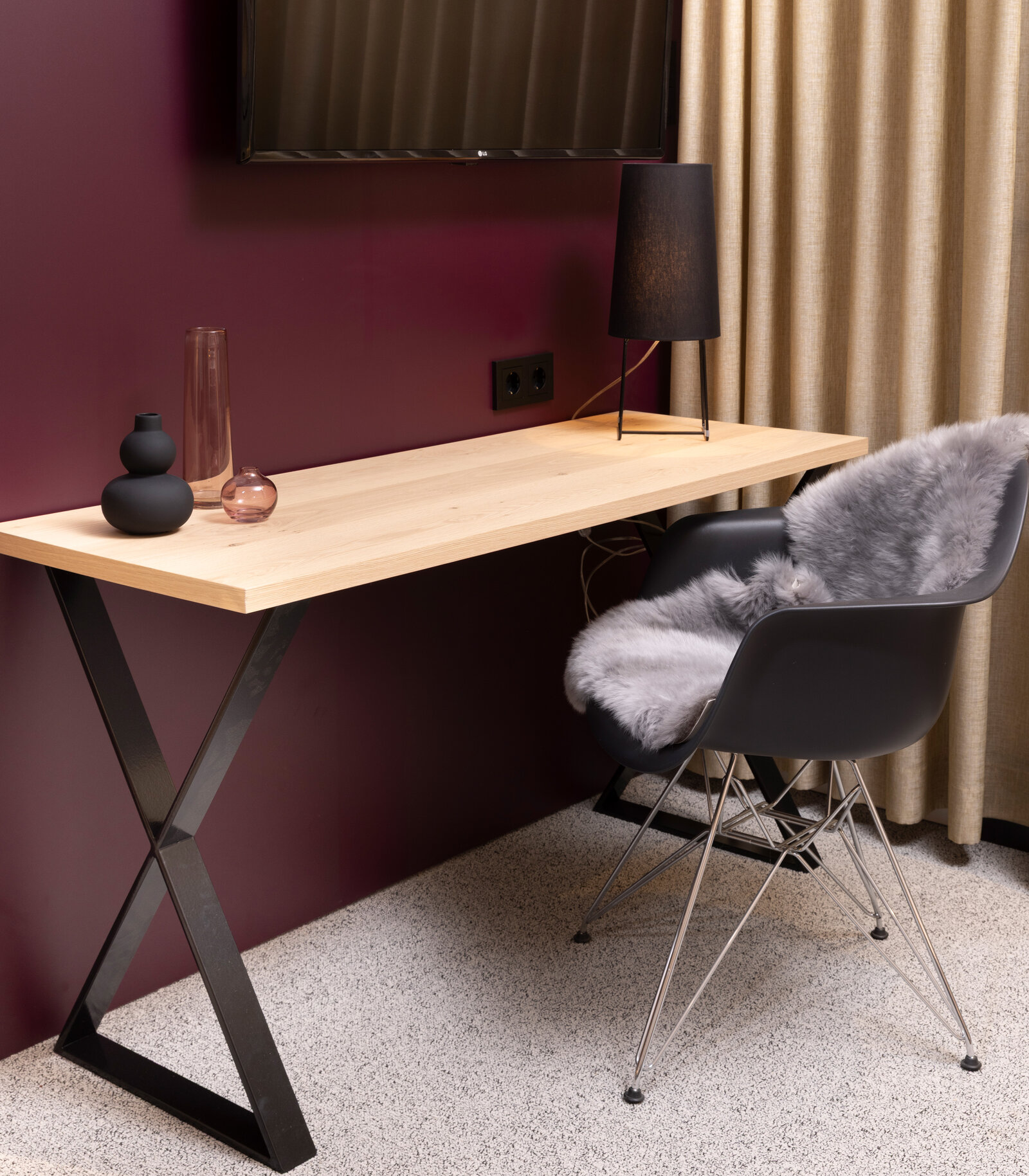 zieflekoch musterzimmer zenit, Schreibtisch mit Holztisch und Metallfüssen in X-Form, schwarzer Stuhl mit grauer Felldecke, schwarze Lampe, Vasen und beigen Vorhängen vor einer Wand in dunklem rot