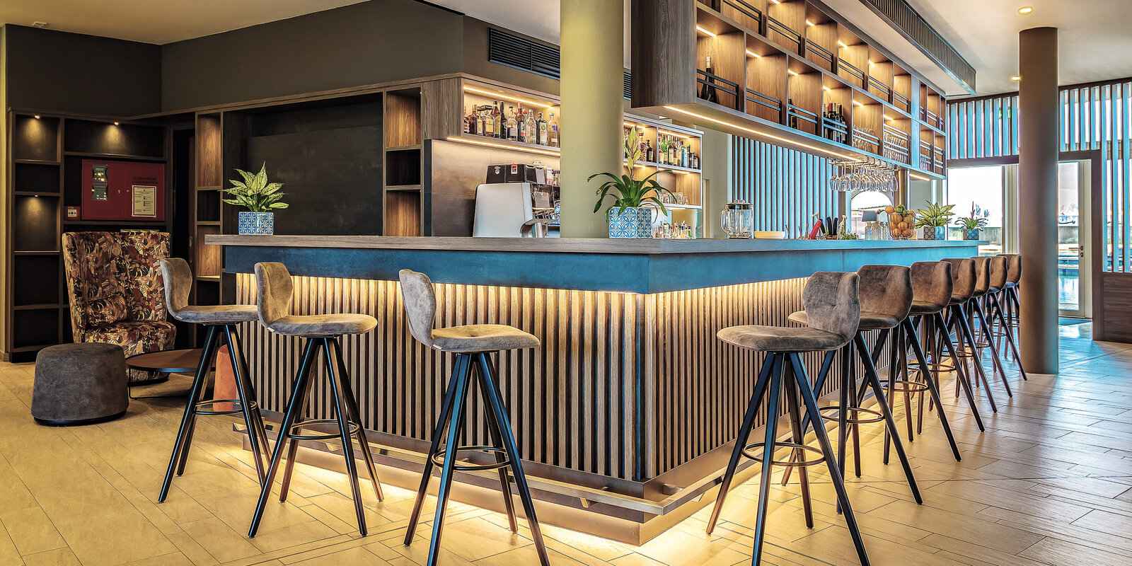 Zieflekoch Hotel Lagovida Ferienresort Rezeption Bar Lobby Raumteiler Lamellenverkleidung Edelstahloptik Regalwand Barhocker Polsterstuhl Sockelbeleuchtung