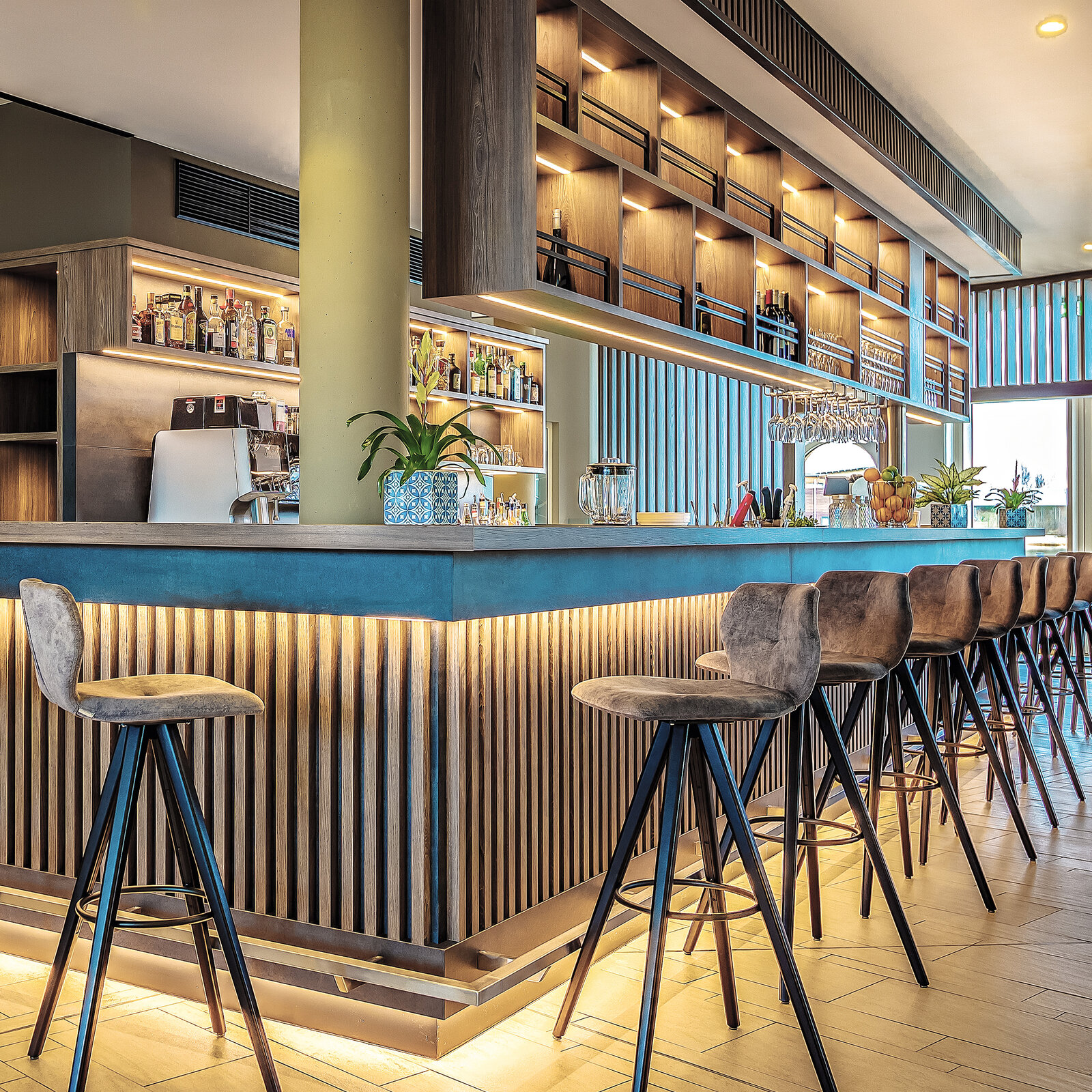 Zieflekoch Hotel Lagovida Ferienresort Rezeption Bar Lobby Raumteiler Lamellenverkleidung Edelstahloptik Regalwand Barhocker Polsterstuhl Sockelbeleuchtung