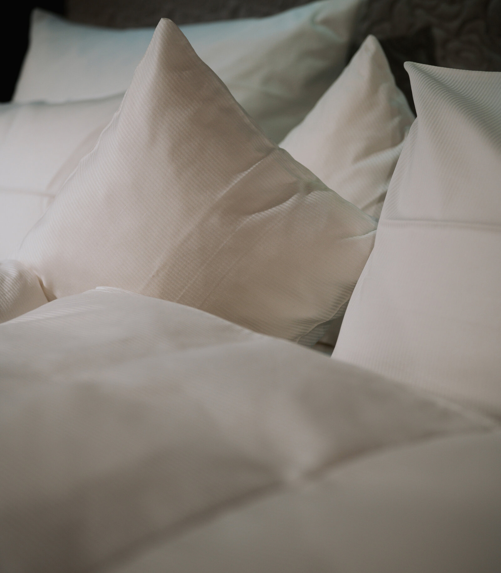 Moodbild_zieflekoch_Hotelbett A neatly arranged bed with fluffy white pillows and a soft comforter, creating a cozy and inviting atmosphere.